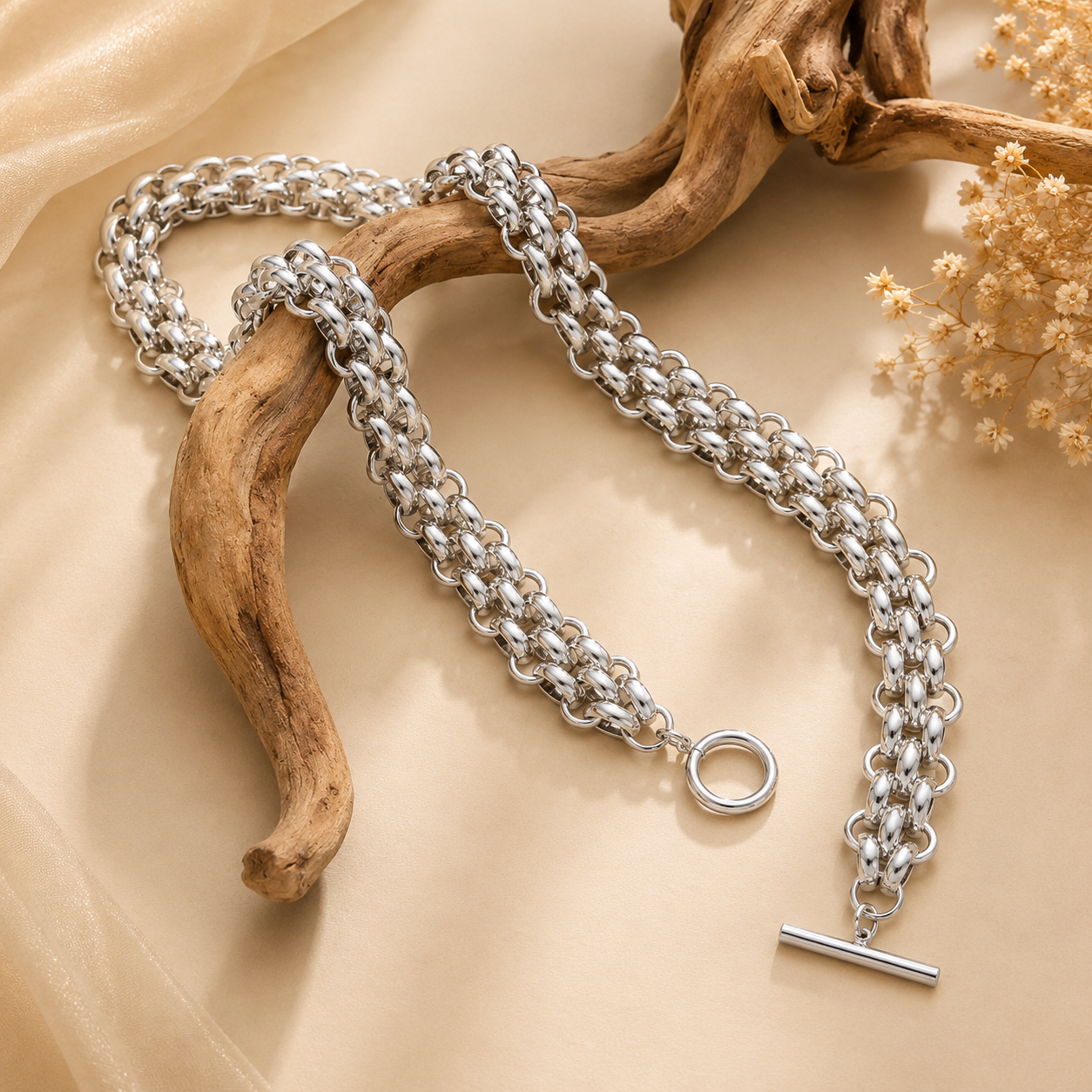 Silver chain bracelet with a clasp on a beige surface with natural elements.