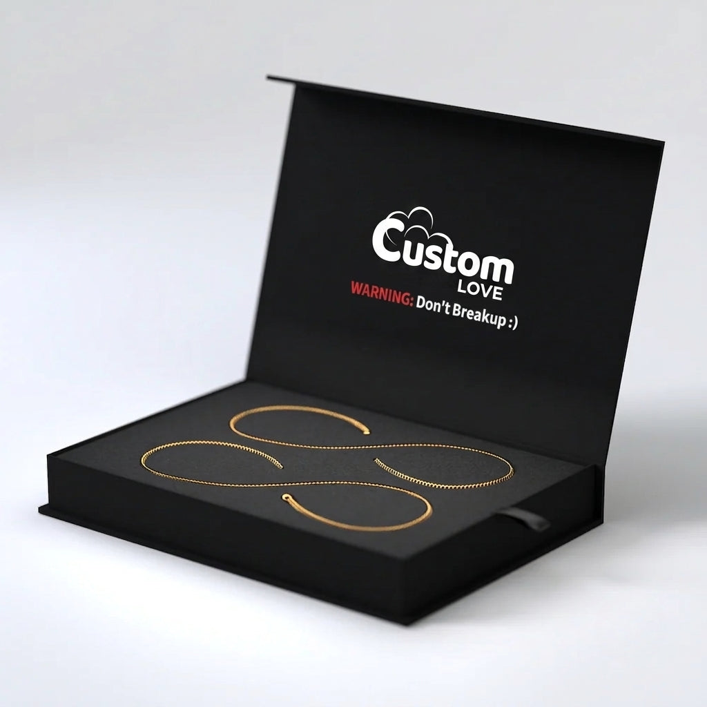 An open black presentation box on a light gray background, containing three delicate curved jewelry pieces in gold, yellow, and rose gold tones. The inside lid has white and red text reading 'Custom LOVE WARNING: Don't Breakup :)'.