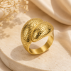 Gold ring with textured design on a beige surface