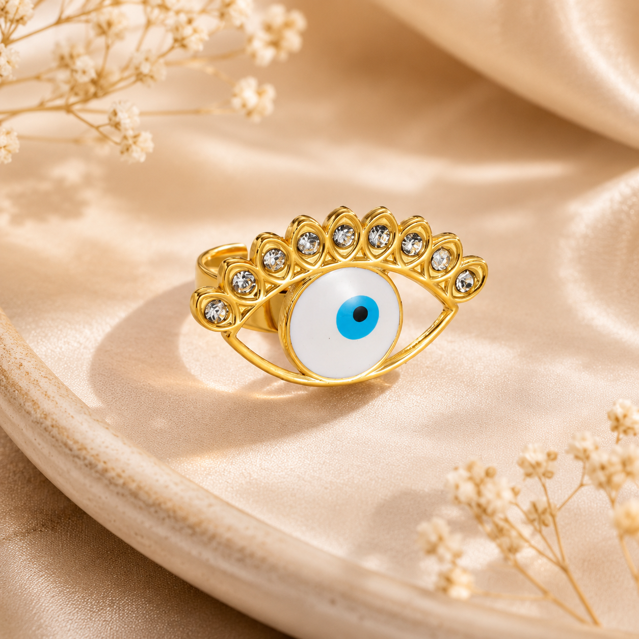 Gold ring with an eye design on a beige fabric background