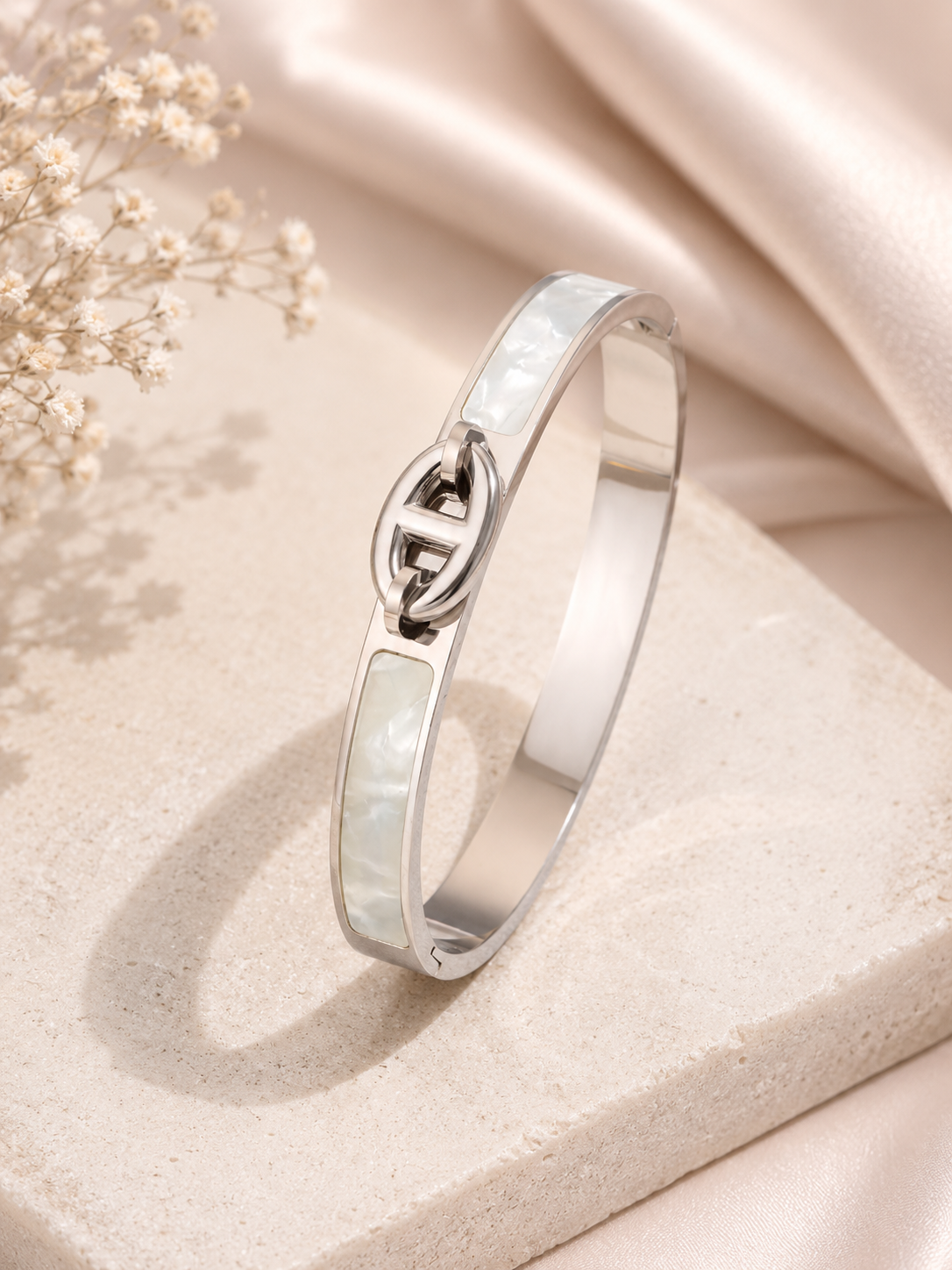 Silver bracelet with a Celtic knot design on a soft beige fabric background